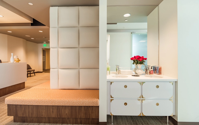 Trommeter Orthodontics | Waiting area at Trommeter Orthodontics with cushioned seating and a decorative vanity with flowers.