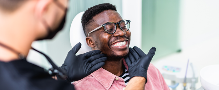 Trommeter Orthodontics | Orthodontist adjusting a smiling patient's jaw during a dental exam.