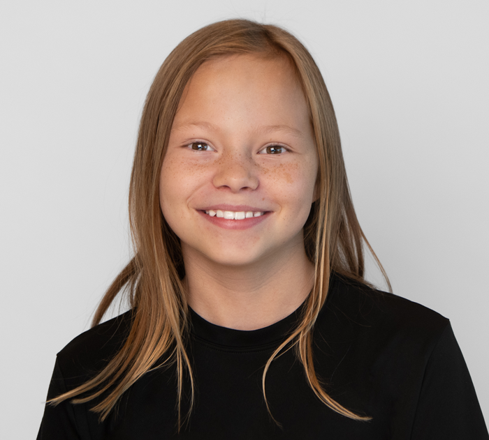 Trommeter Orthodontics | Portrait of a smiling young girl with straight light brown hair, wearing a black shirt.